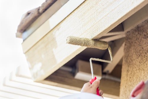 Painter rolling fresh paint onto exterior trim on a metro Atlanta home